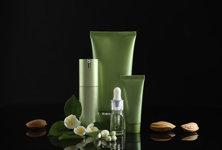 Set of cosmetic products, almond nuts and flowers on black backgroundの写真素材