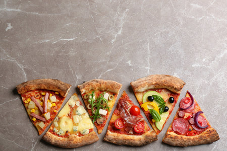 Slices of different delicious pizzas on gray marble table, flat lay. Space for textの写真素材
