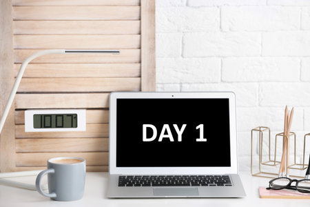 Start new job. Laptop with text Day 1 on screen in modern officeの写真素材