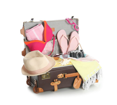 Open vintage suitcase with different beach objects packed for summer vacation isolated on whiteの写真素材