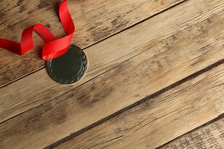 Medal with red ribbon on wooden background, top view. space for designの写真素材