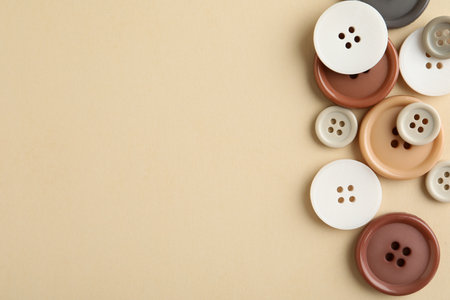 Many colorful sewing buttons on beige background, flat lay. Space for textの写真素材