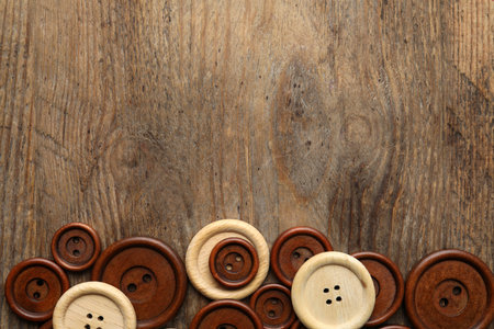 Many sewing buttons on wooden background, flat lay. Space for textの写真素材