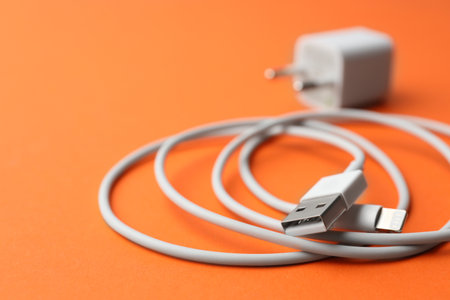 USB charge cable on orange background, closeup. Space for text