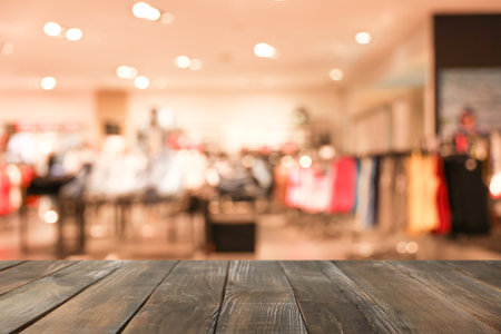 Empty wooden table and blurred view of store with modern clothesの写真素材
