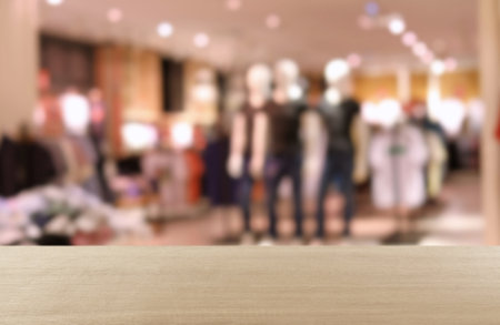 Empty wooden table and blurred view of store with modern clothesの写真素材