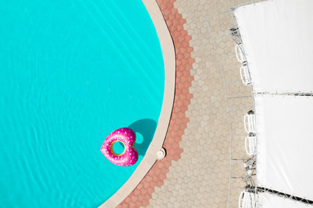 Heart shaped inflatable ring floating in swimming pool, top view. summer holidays