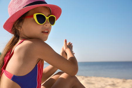 Cute little child sitting at sandy beach on sunny dayの写真素材