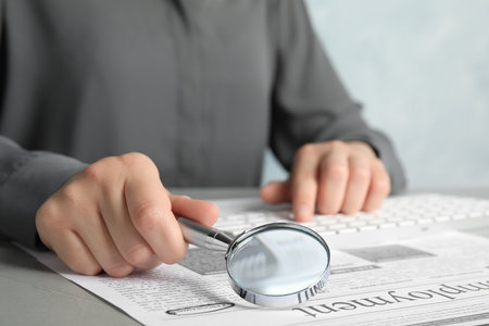 Woman looking through magnifying glass at newspaper, closeup. job search conceptの写真素材
