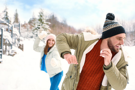 Happy couple playing snowballs outdoors. winter holidays