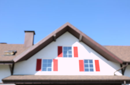 Blurred view of building with windows and red shutters on sunny day