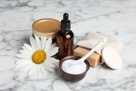 Composition with chamomile flower and cosmetic products on white marble tableの写真素材