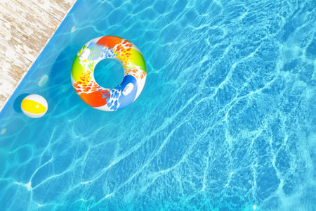 Swimming pool with inflatable ring and ball, top view. Space for text