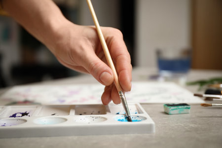 Woman painting with watercolor at gray stone table, closeupの写真素材