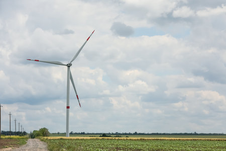 Modern wind turbine in field on cloudy day. Alternative energy source