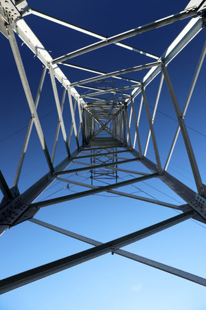 Modern high voltage tower against blue sky, bottom view