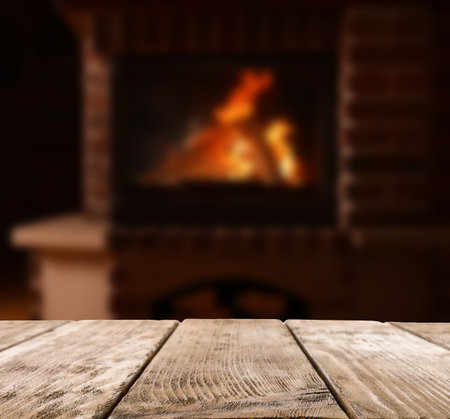Rustic table and fireplace with burning wood indoorsの写真素材