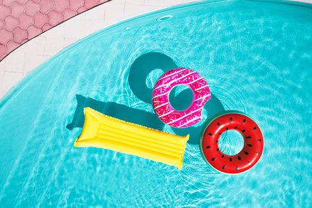 Inflatable rings and mattress floating in swimming pool, top view. summer holidays