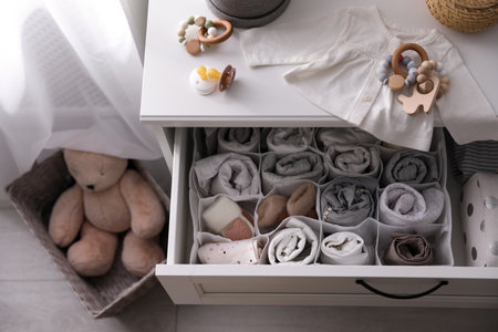 Modern open chest of drawers with baby clothes and accessories in room, above viewの写真素材