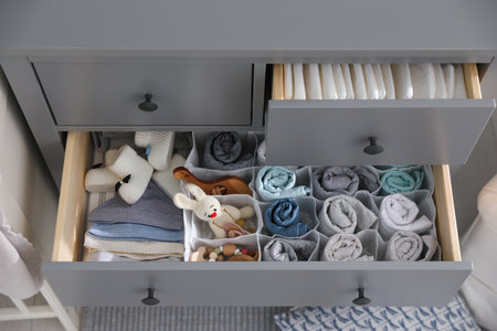 Modern open chest of drawers with clothes and accessories in baby room, above viewの写真素材