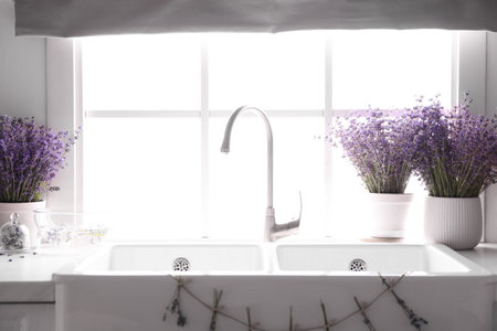 Beautiful lavender flowers on countertop near sink in kitchenの写真素材