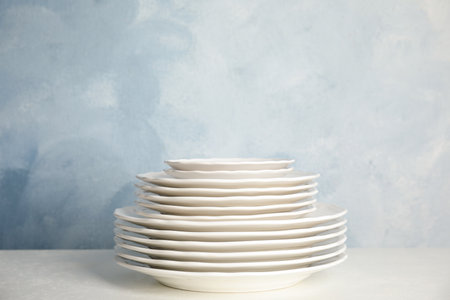 Stack of clean plates on table against light blue background. Space for text