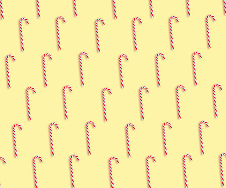 Pattern of Christmas candy canes on pale yellow background, top viewの写真素材