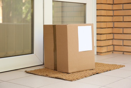Delivered parcel on door mat near entranceの写真素材