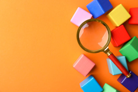 Different colorful cubes and magnifier glass on orange background, flat lay with space for text. Find keywords conceptの写真素材
