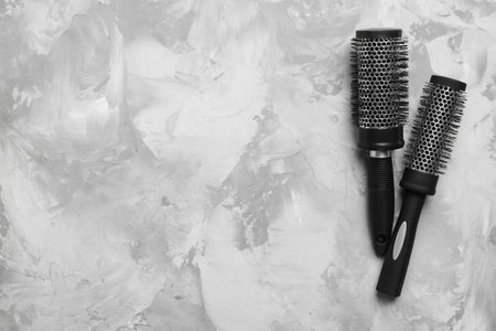 Hair brushes on light gray stone background, flat lay. Space for textの写真素材