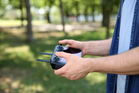 Man holding new modern drone controller outdoors, closeup of hands