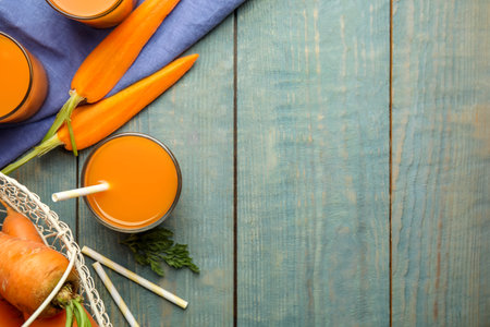 Freshly made carrot juice on wooden table, flat lay. Space for textの写真素材