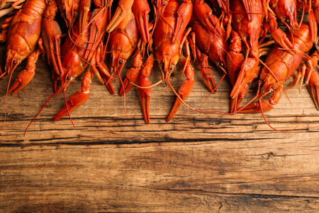 Delicious boiled crayfishes on wooden table, flat lay. Space for textの写真素材