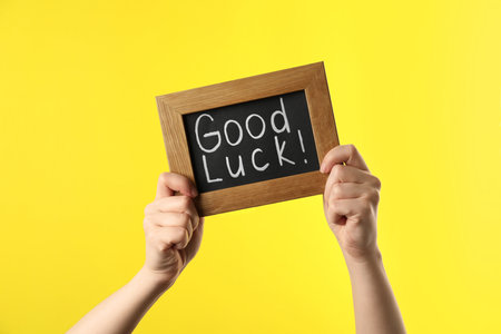 Woman holding blackboard with words GOOD LUCK on yellow background, closeupの写真素材
