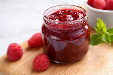 Delicious jam and fresh raspberries on wooden board, closeupの写真素材