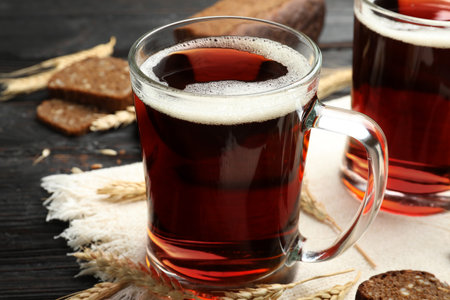 Mugs of delicious kvass, spikes and bread on table