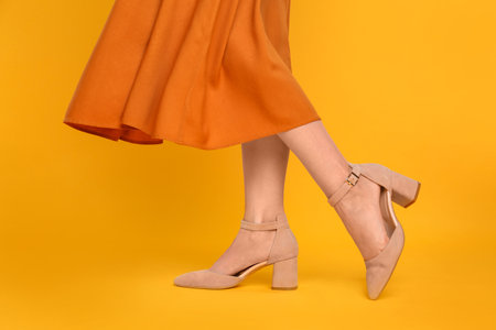 Woman wearing stylish shoes on yellow background, closeup