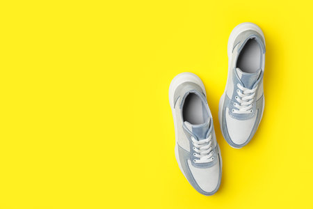 Stylish sneakers on yellow background, flat lay. Space for textの写真素材