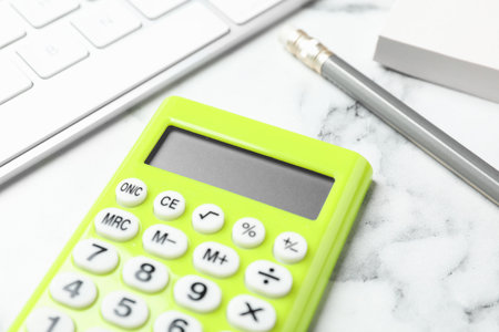 Calculator, keyboard and stationery on white marble table, closeup. tax accounting