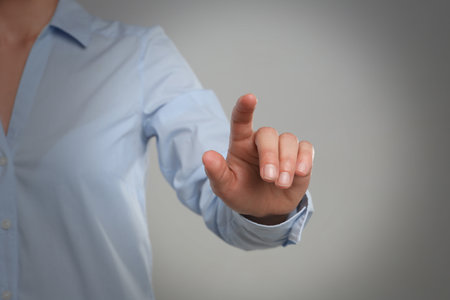 Woman touching something against gray background, focus on hand