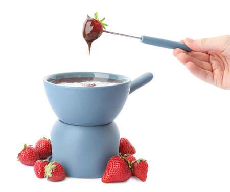Woman dipping strawberry into fondue pot with chocolate on white background, closeupの写真素材