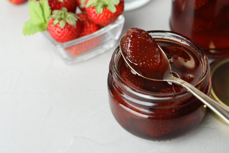 Delicious pickled strawberry jam and fresh berries on light table. Space for text
