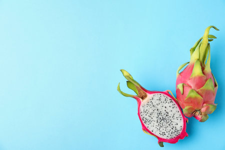Delicious cut and whole dragon fruits (pitahaya) on light blue background, flat lay. Space for textの写真素材