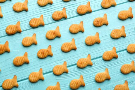 Delicious goldfish crackers on light blue wooden table, flat lay
