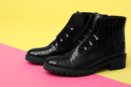 Pair of stylish ankle boots on color background