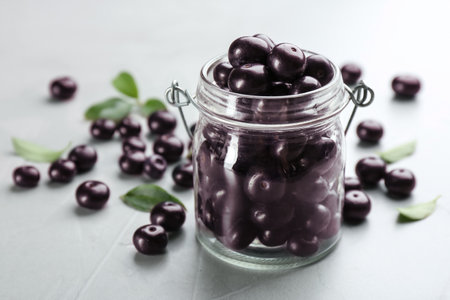 Fresh acai berries in glass jar on light gray table, closeupの写真素材