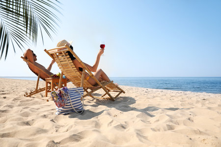 Couple with wine on sunny beach at resortの写真素材