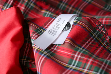 Clothing label with size and content information on red plaid garment, closeupの写真素材
