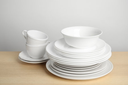 Clean plates, bowl and cups on wooden table against white backgroundの写真素材