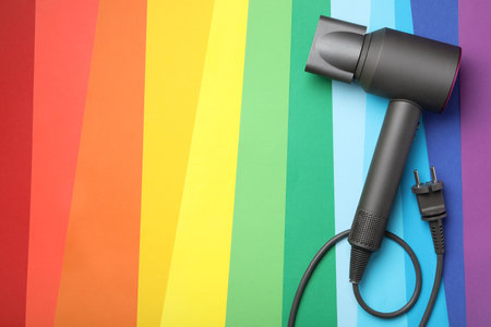 Hair dryer on rainbow background, top view with space for text. Professional hairdresser toolの写真素材